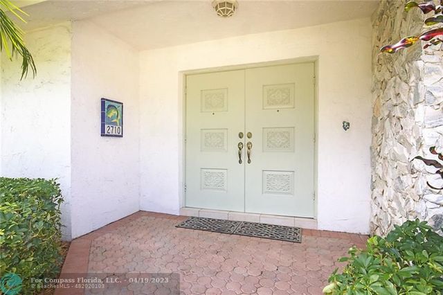 a palm tree sitting in front of a house with wooden fence