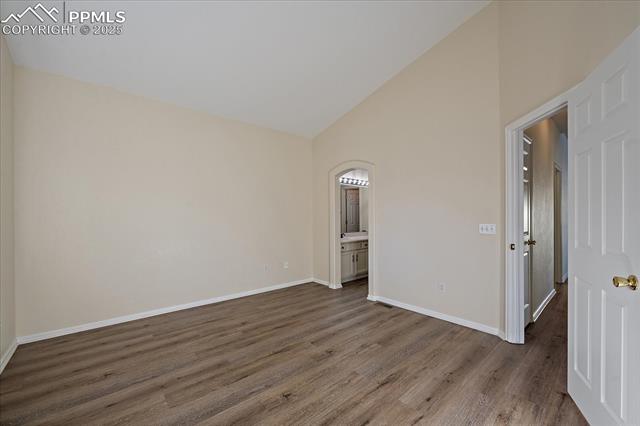 1110 Samuel Point Colorado Springs, CO 80906 - Photo 20 of 28 Empty room with wood finished floors, high vaulted ceiling, and arched walkways