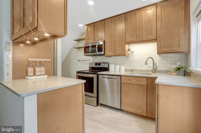 a view of a hallway with wooden floor and a bathroom