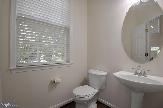 a bathroom with a toilet a sink a mirror and a window