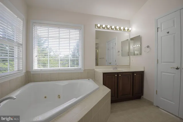 a bathroom with a tub a double vanity sink and a window