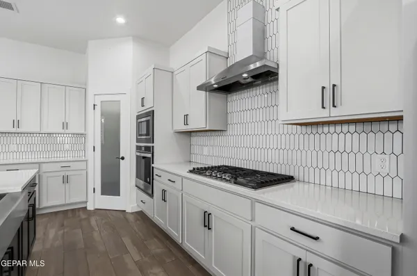 a large white kitchen with kitchen island a sink stainless steel appliances and a fireplace