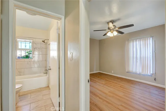 a view of a hallway with wooden floor and a bathroom
