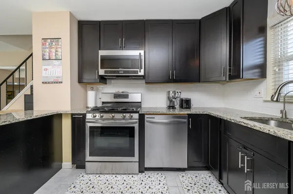 a kitchen with stainless steel appliances kitchen island granite countertop a sink stove and microwave