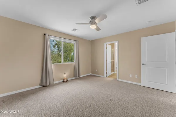 an empty room with chandelier fan and windows