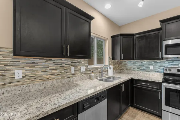 a kitchen with granite countertop stainless steel appliances a sink stove and microwave