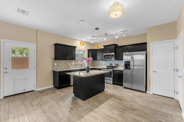 a large kitchen with a stove a sink dishwasher a refrigerator and a fireplace with wooden floor