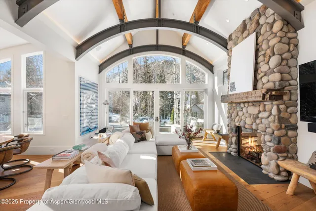 a living room with furniture a fireplace and large windows