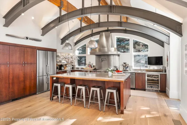 a open kitchen with stainless steel appliances granite countertop a stove a refrigerator and a dining table with wooden floor