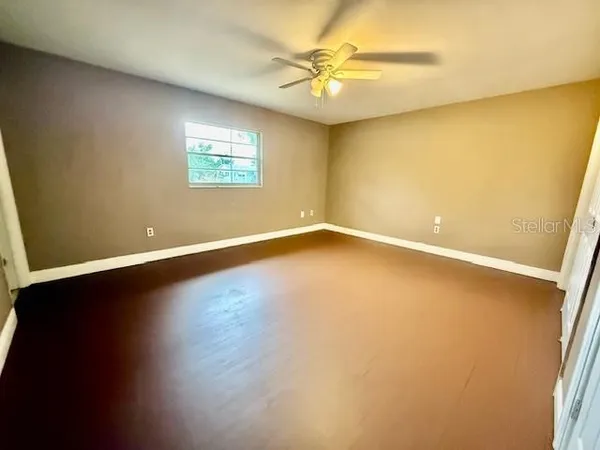 an empty room with a window and a ceiling fan