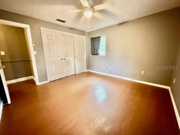 an empty room with a ceiling fan and window