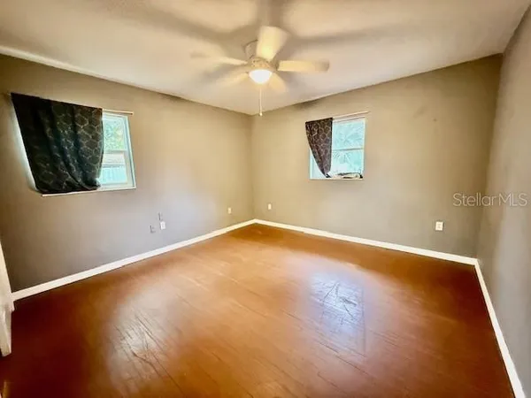 an empty room with wooden floor and windows