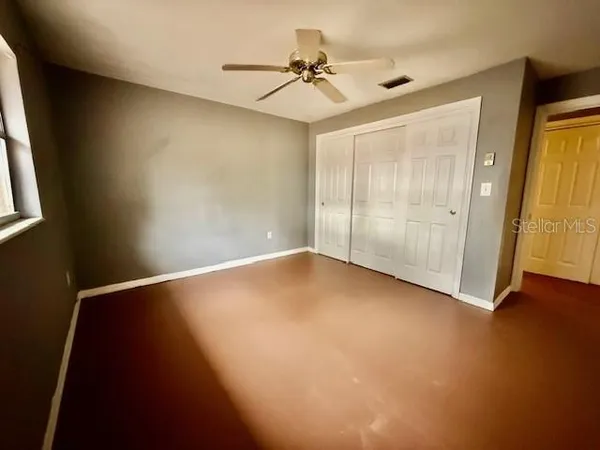 an empty room with a window and a fan