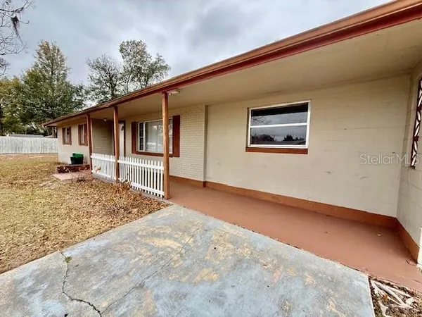 a backyard of a house with large trees and wooden fence