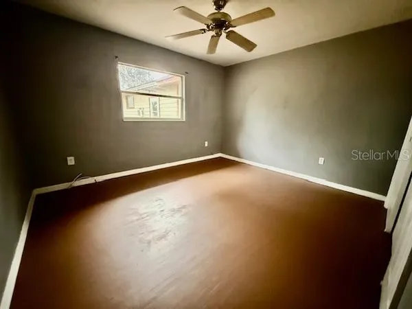 an empty room with windows and fan