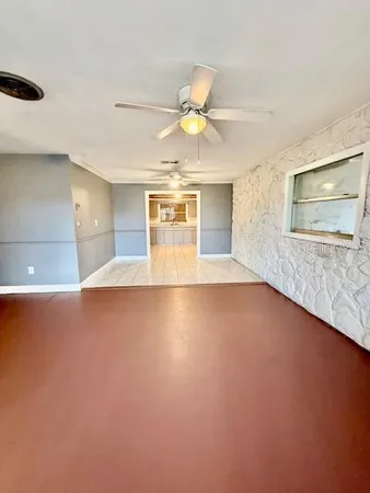 a view of an empty room with window and wooden floor