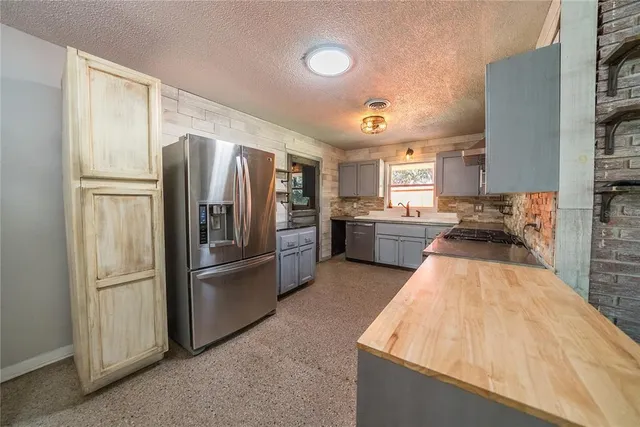 a kitchen with stainless steel appliances kitchen island granite countertop a refrigerator and a stove top oven
