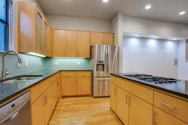 a kitchen with stainless steel appliances granite countertop a refrigerator and a stove top oven