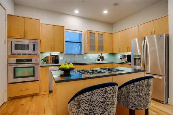 a kitchen with stainless steel appliances granite countertop a stove refrigerator sink and microwave