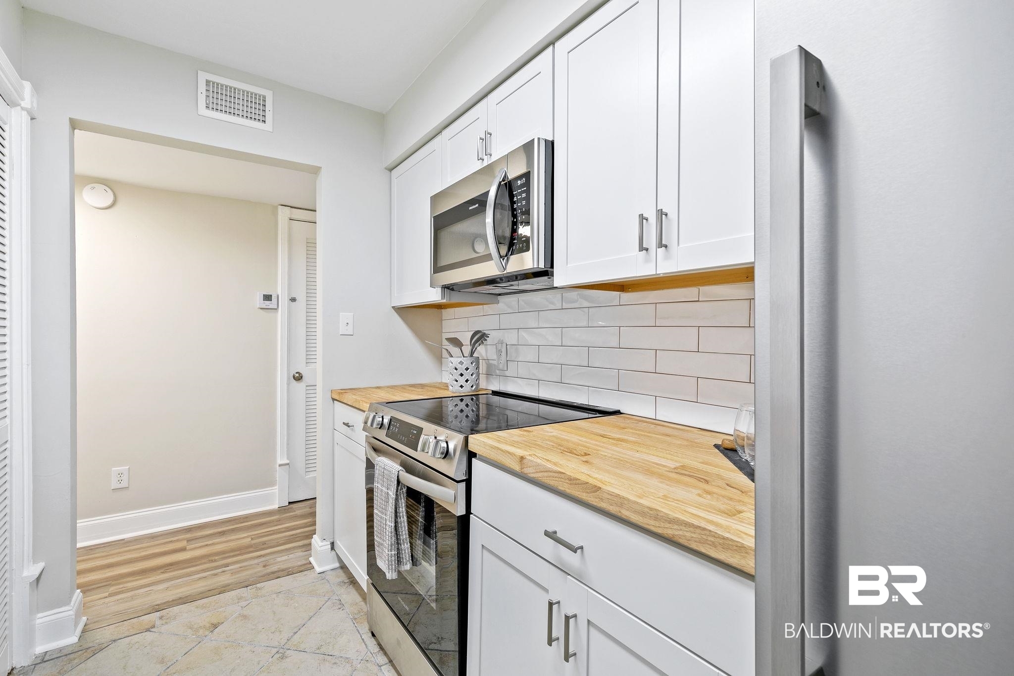110 5th Street, Unit C103 Daphne, AL 36526 - Photo 22 of 46 Kitchen featuring white cabinets, light hardwood / wood-style flooring, backsplash, stainless steel appliances, and wood counters