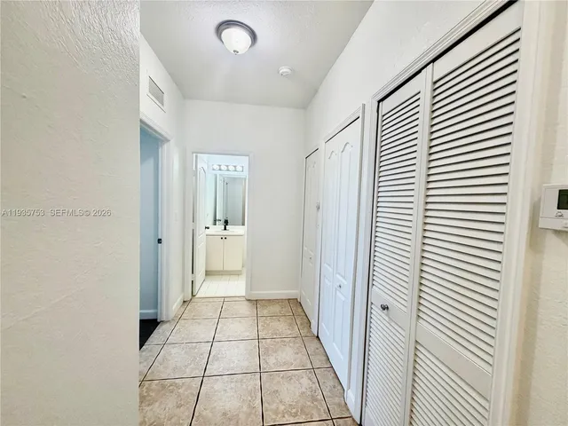 a view of a hallway with a door and refrigerator