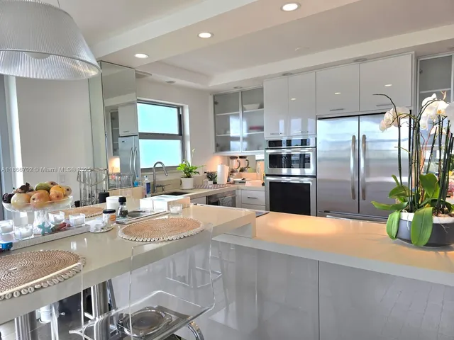 a large kitchen with kitchen island a large counter top stainless steel appliances and cabinets