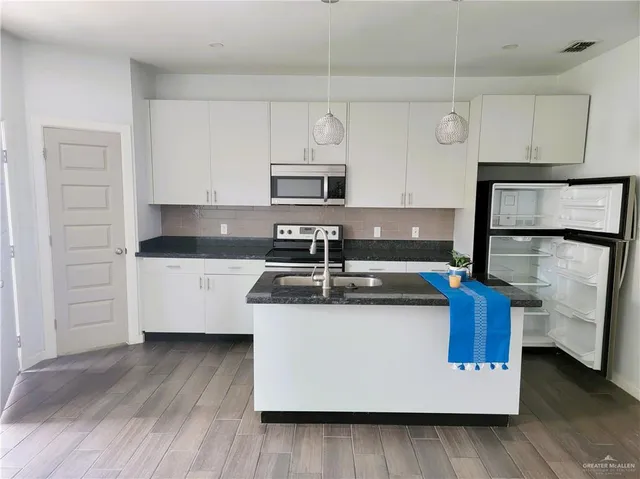 a white kitchen with sink and wooden floor