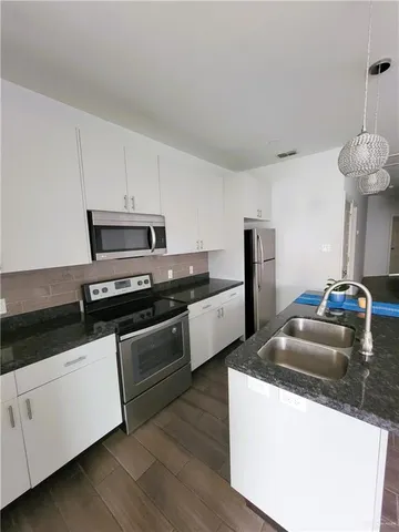 a kitchen with granite countertop a sink a counter top space stainless steel appliances and cabinets