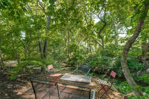 a backyard of a house with table and chairs under an umbrella