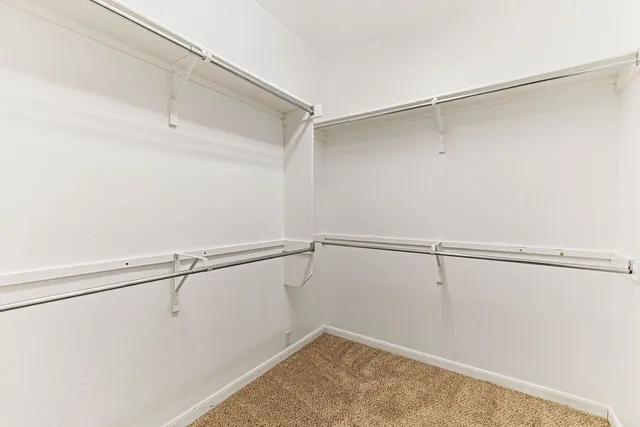 an empty room with chandelier fan and windows