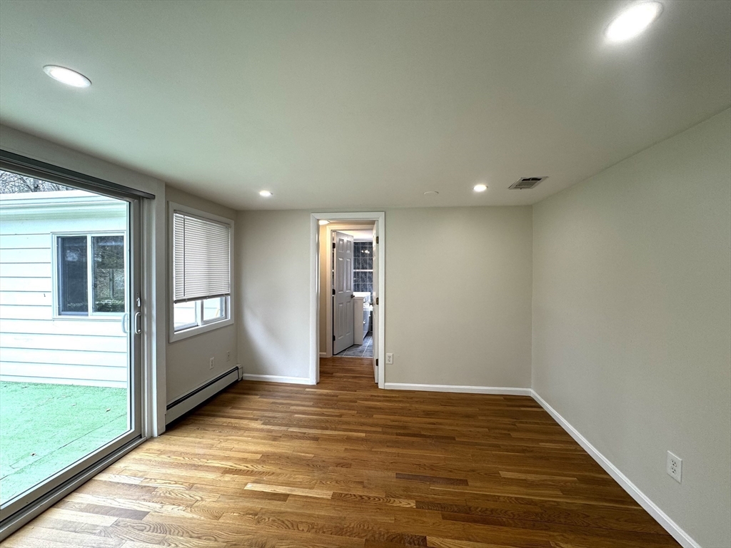 115 Grove Street Brookline, MA 02467 - Photo 5 of 12 a view of an empty room with window and wooden floor