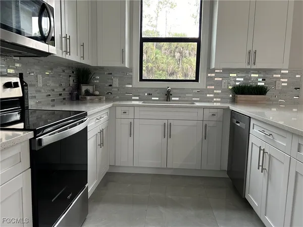 a kitchen with cabinets appliances a sink and a window