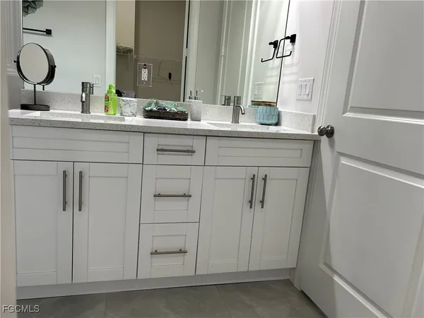 a bathroom with a double vanity sink and a mirror with toilet