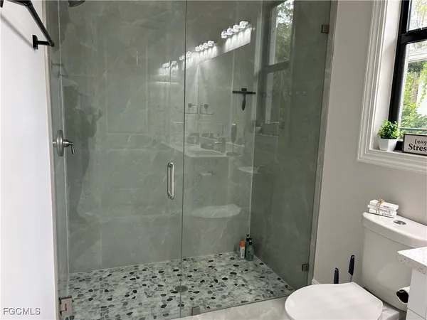 a bathroom with a shower a toilet and a window