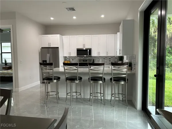 a kitchen with stainless steel appliances granite countertop a stove top oven a sink a dining table and chairs