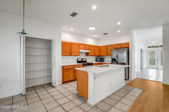 a kitchen with stainless steel appliances a stove top oven a sink a refrigerator and cabinets
