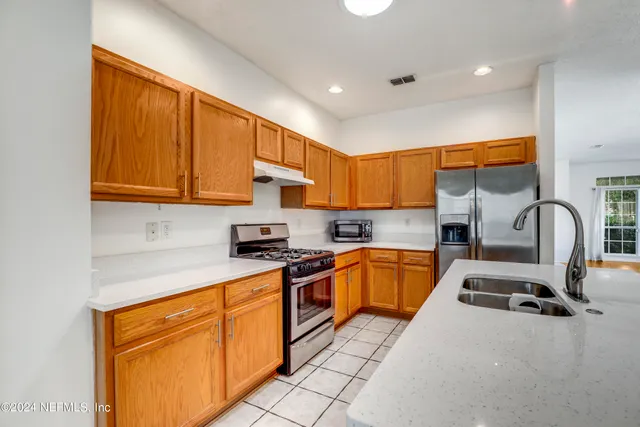 a kitchen with stainless steel appliances granite countertop a stove a sink and a microwave