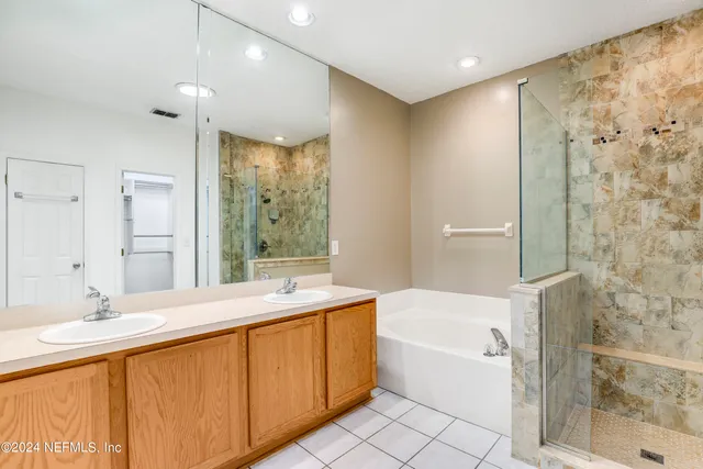 a bathroom with a granite countertop sink a mirror a bathtub and shower