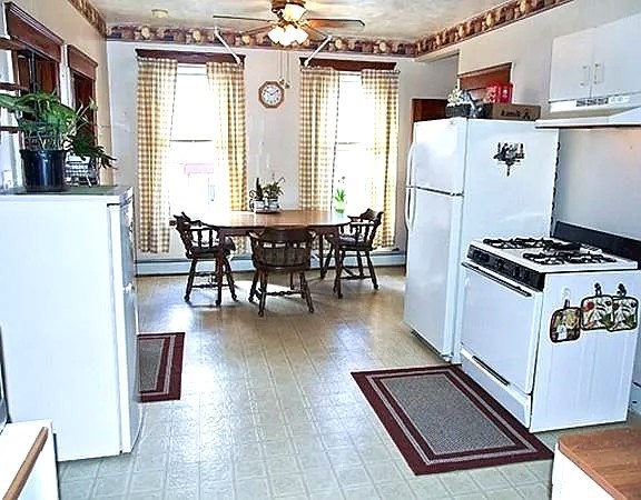 56 Plantation Street Worcester, MA 01604 - Photo 10 of 18 a kitchen with stainless steel appliances a refrigerator a stove a dining table and chairs with wooden floor