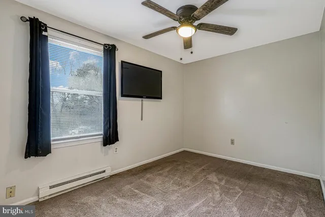 an empty room with windows and fan