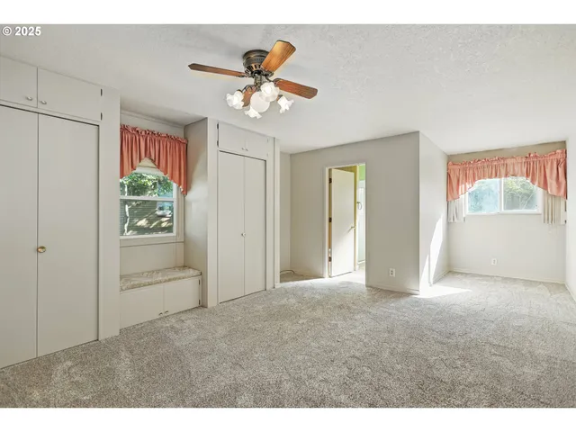 a view of empty room with window and ceiling fan