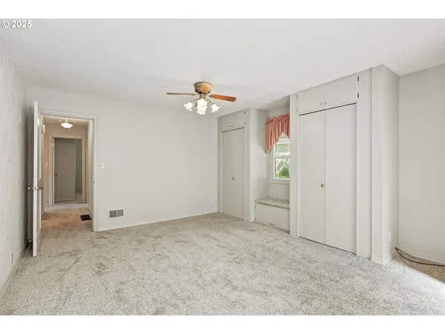 a view of an empty room with chandelier fan
