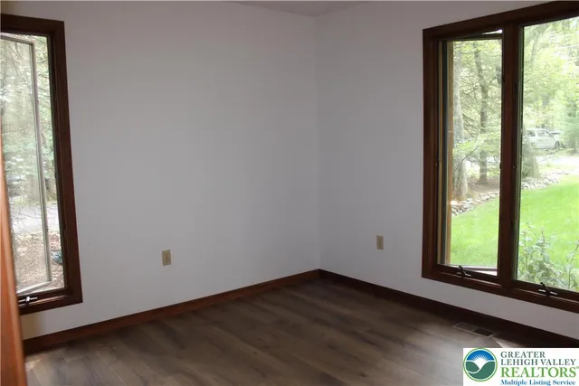 a view of an empty room and wooden floor and windows