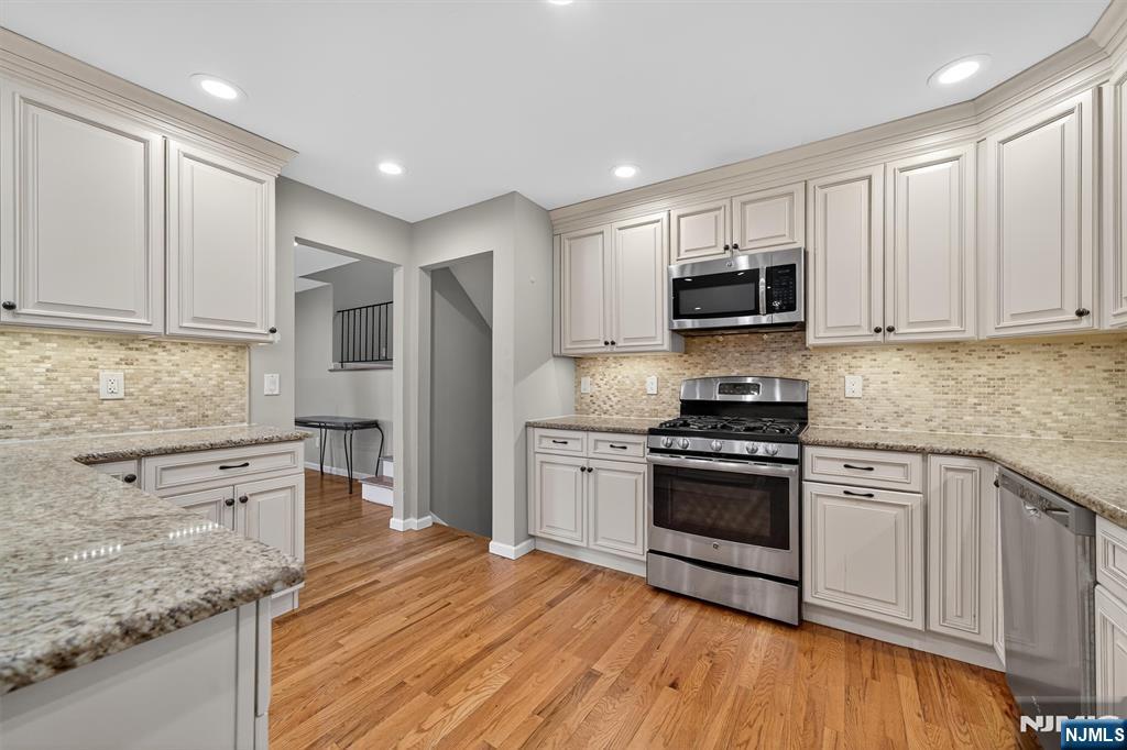 7 Faber Place Nutley, NJ 07110 - Photo 9 of 41 a kitchen with granite countertop a stove top oven a sink dishwasher and a refrigerator with wooden floor