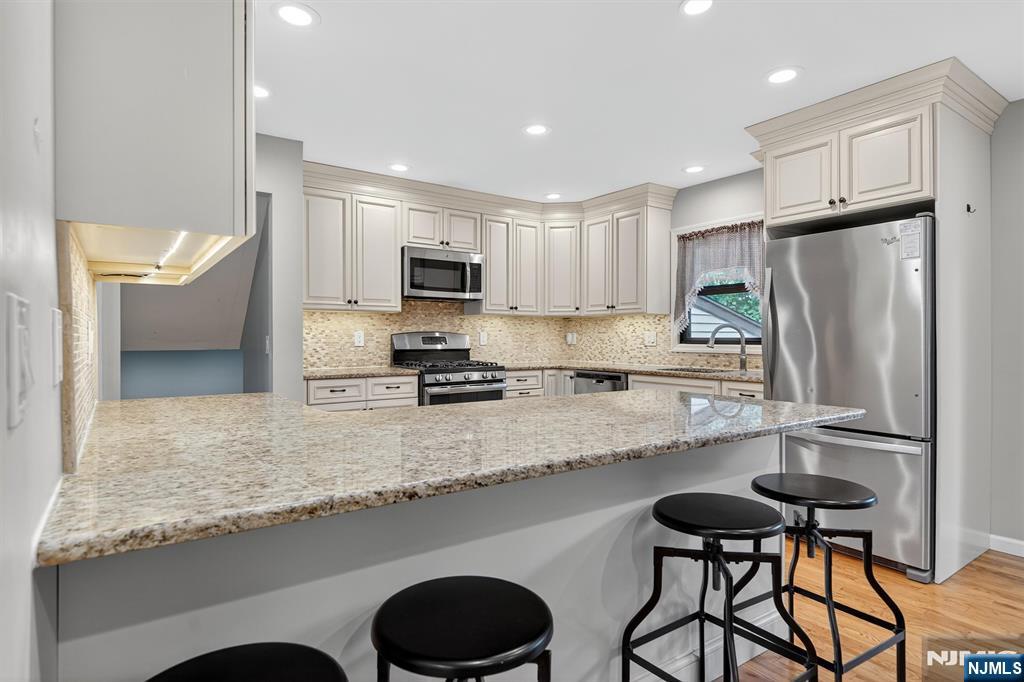 7 Faber Place Nutley, NJ 07110 - Photo 10 of 41 a kitchen with kitchen island granite countertop a sink a stove a refrigerator cabinets and a dining table with wooden floor
