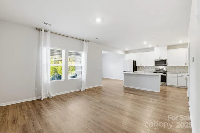 a large kitchen with kitchen island a stove a sink dishwasher and white cabinets with wooden floor