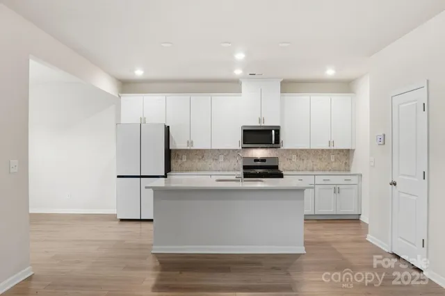 a kitchen with kitchen island white cabinets and stainless steel appliances