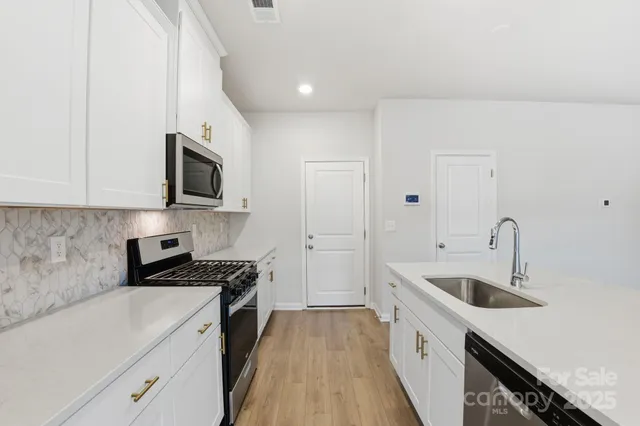 a kitchen with stainless steel appliances granite countertop a sink and a stove