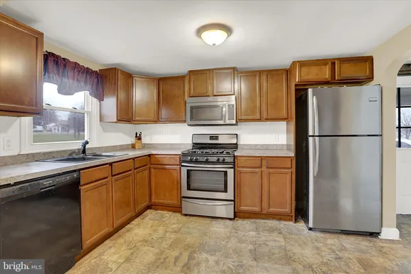 a kitchen with granite countertop a refrigerator stove and sink