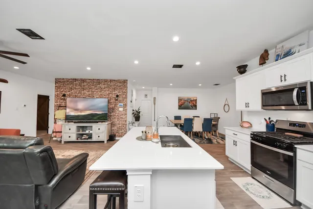 a large kitchen with stainless steel appliances a stove a sink a refrigerator and cabinets